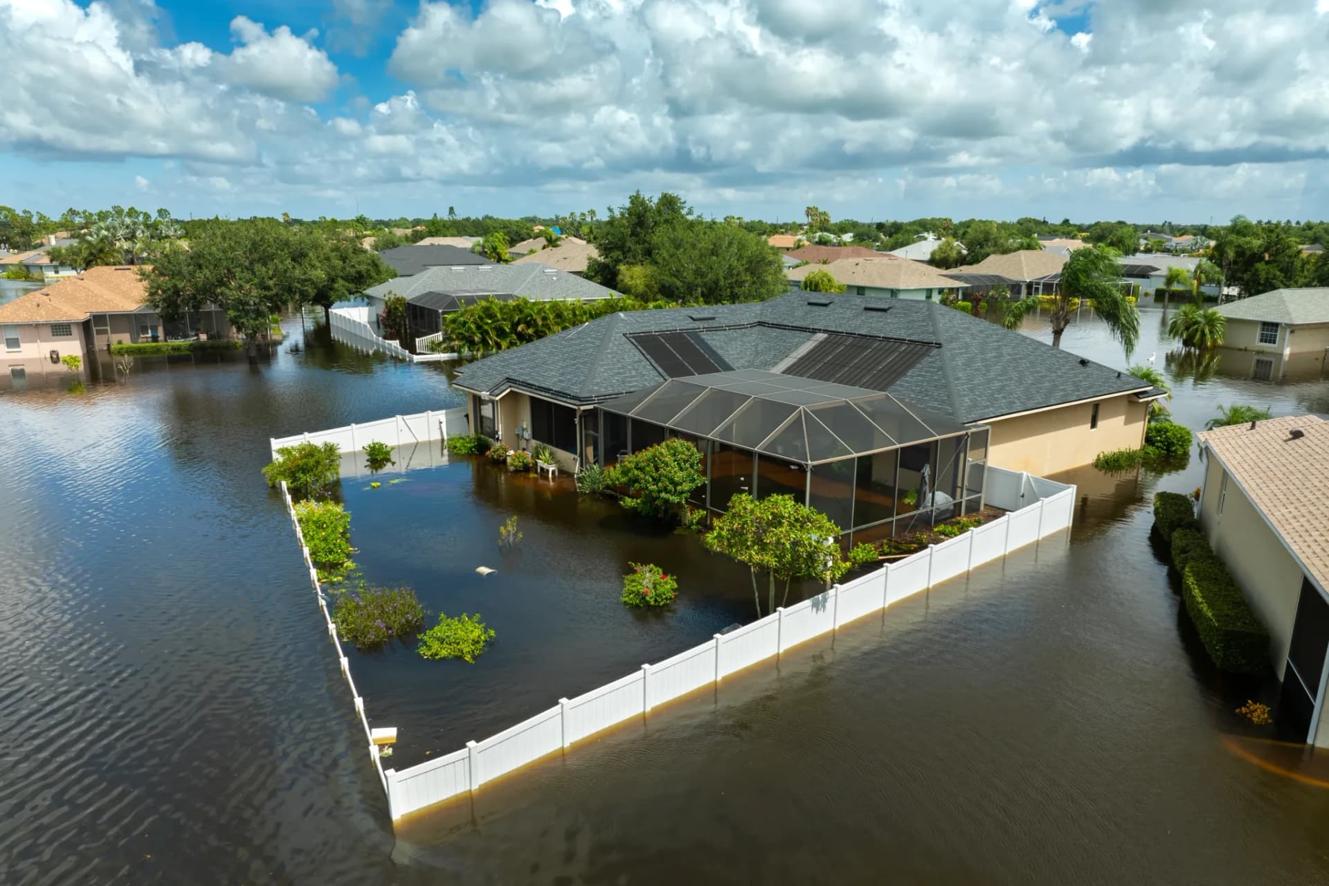 A neighborhood under floodwater after a tropical storm, homes and yards submerged to the foundations
